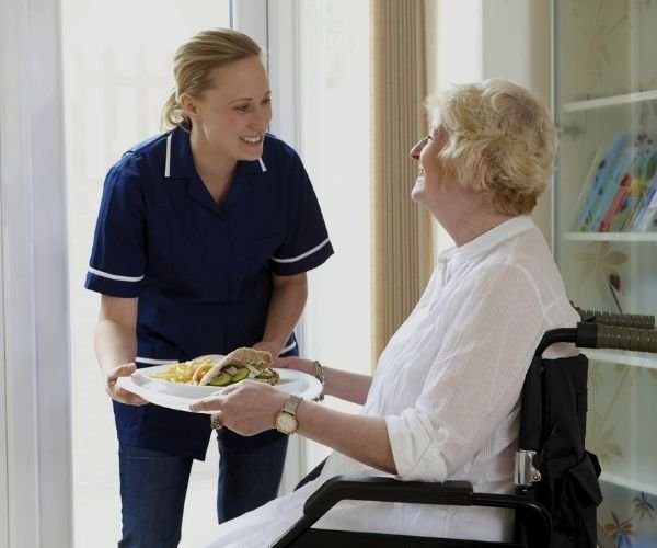 Home health care nurse serving meal